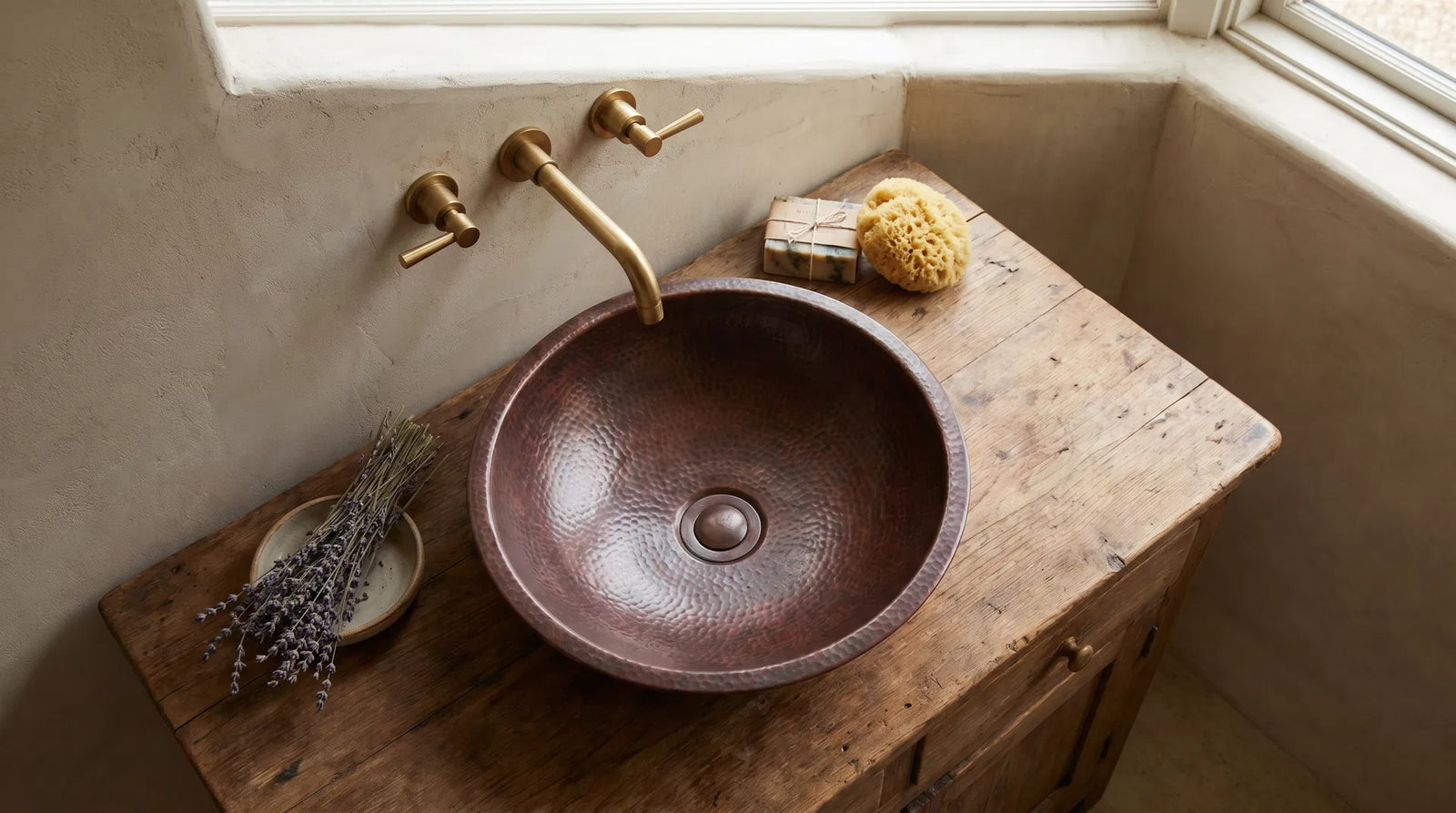 Round hammered copper vessel sink on a natural wood vanity