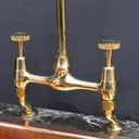 Unlacquered brass curved legs bridge faucet – natural patina close-up