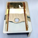 Unlacquered brass farmhouse sink – close-up of apron front and natural patina