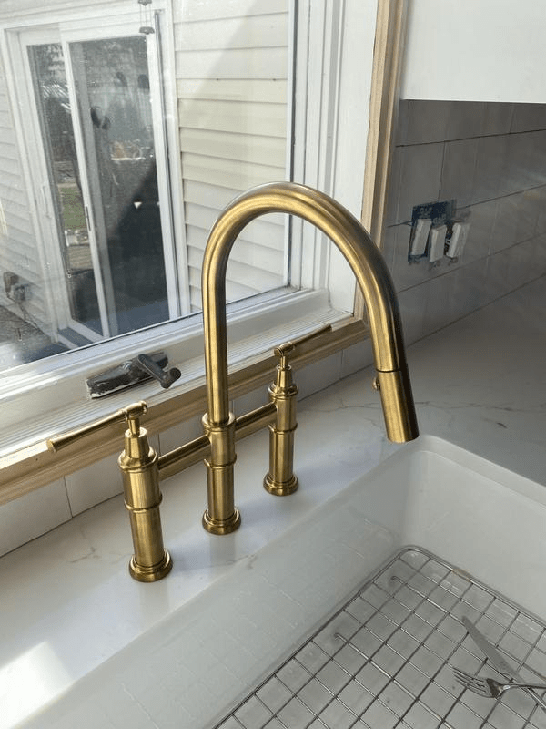 Unlacquered brass bridge faucet with pull-down spray and lever handles – front view