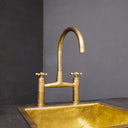 Unlacquered brass bridge faucet with sprayer cross handles – installed in kitchen